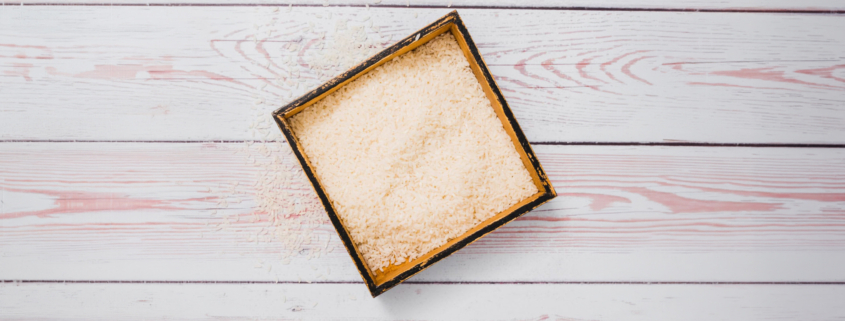 Top view of loose vermiculite granules in a square wooden tray on a light wooden surface.